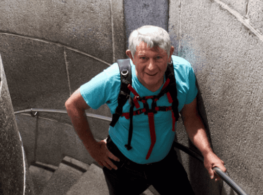 Man in blue shirt with backpack climbing concrete stairs.