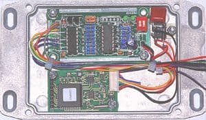 Close-up of electronic circuit board with wiring in metal enclosure.
